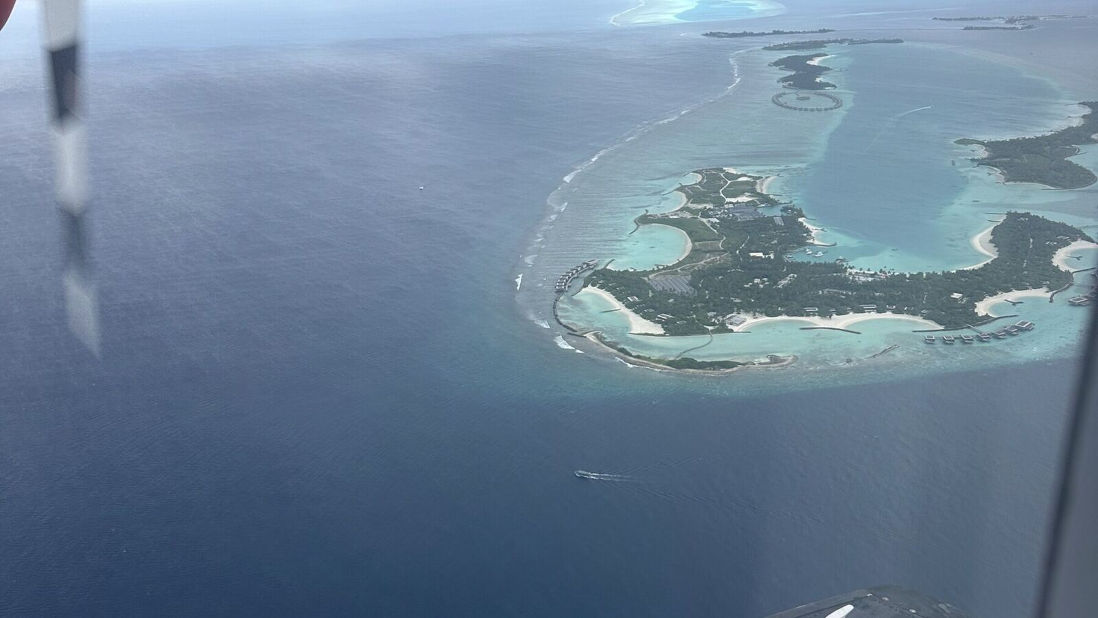 飛行機の窓から見下ろしたモルディブの環礁。青い海に島とリーフが浮かぶ